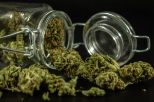 Detailed image of cannabis buds spilling out of a glass jar.