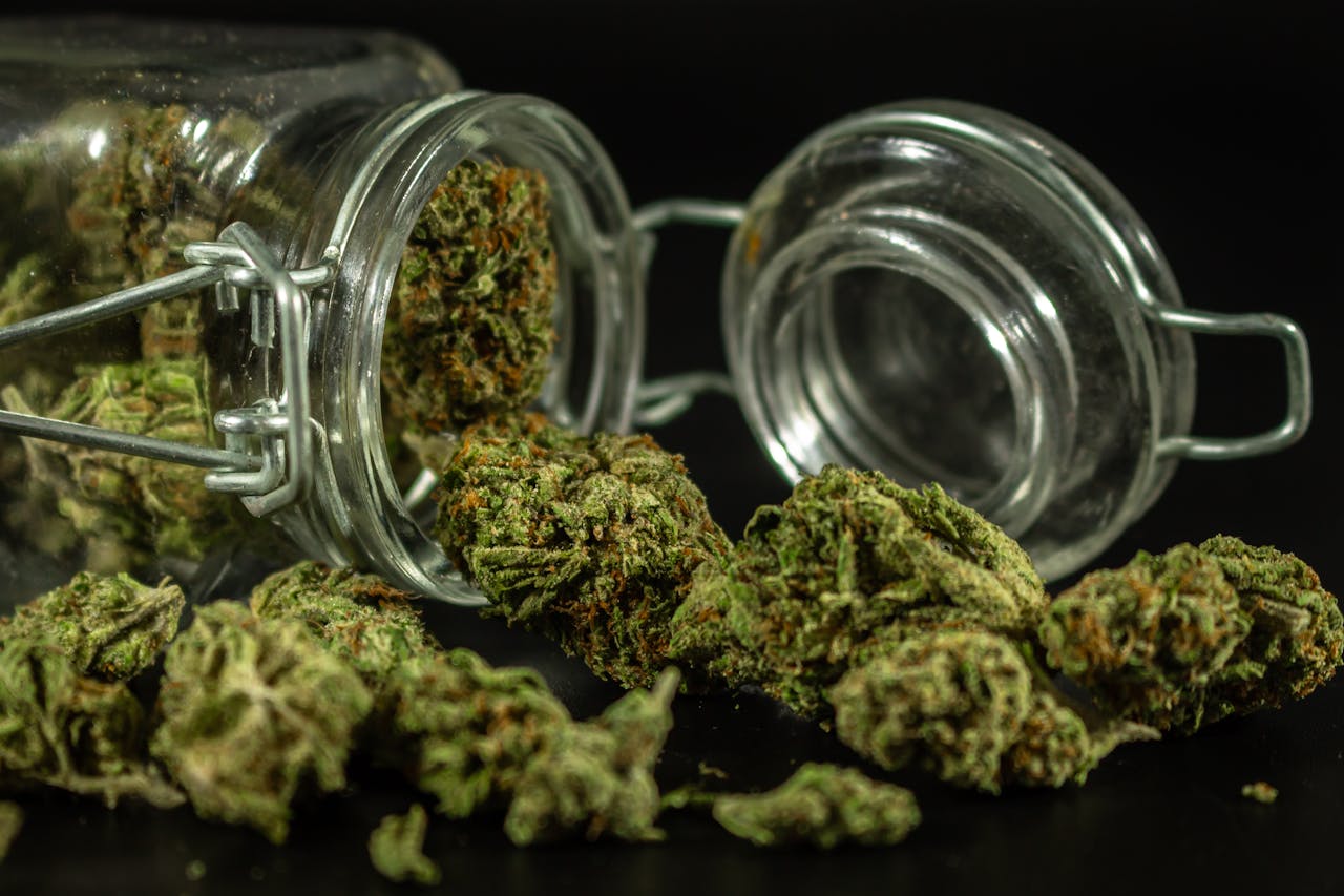 Detailed image of cannabis buds spilling out of a glass jar.